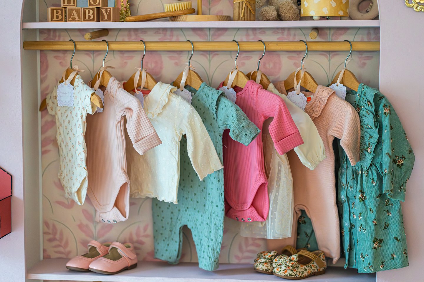 Baby clothes and shoes organized on shelves in a closet.
